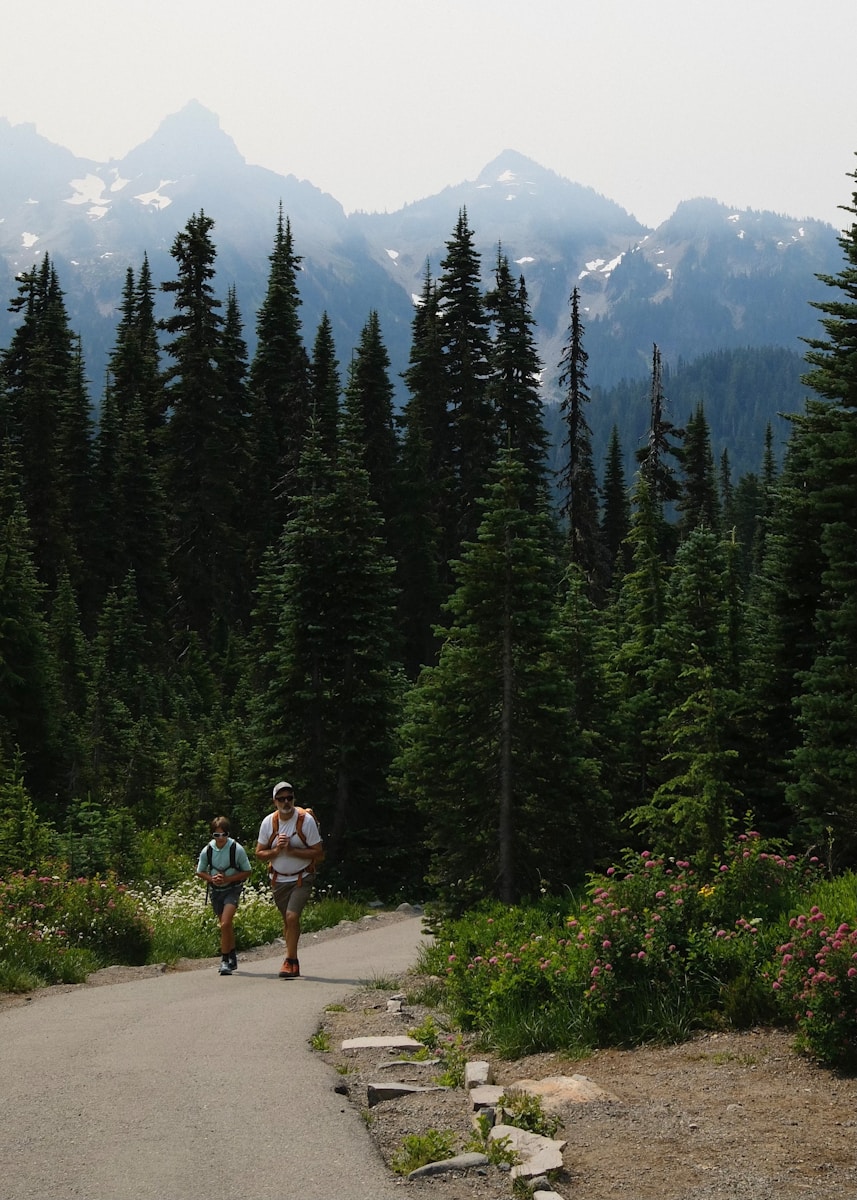A man riding a skateboard down a road next to a forest